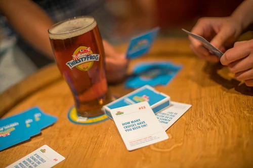friends playing card games and drinking beer at redfrog rum bar on board carnival horizon