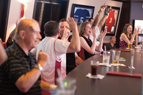 guests celebrating a score at skybox sports bar on board carnival horizon